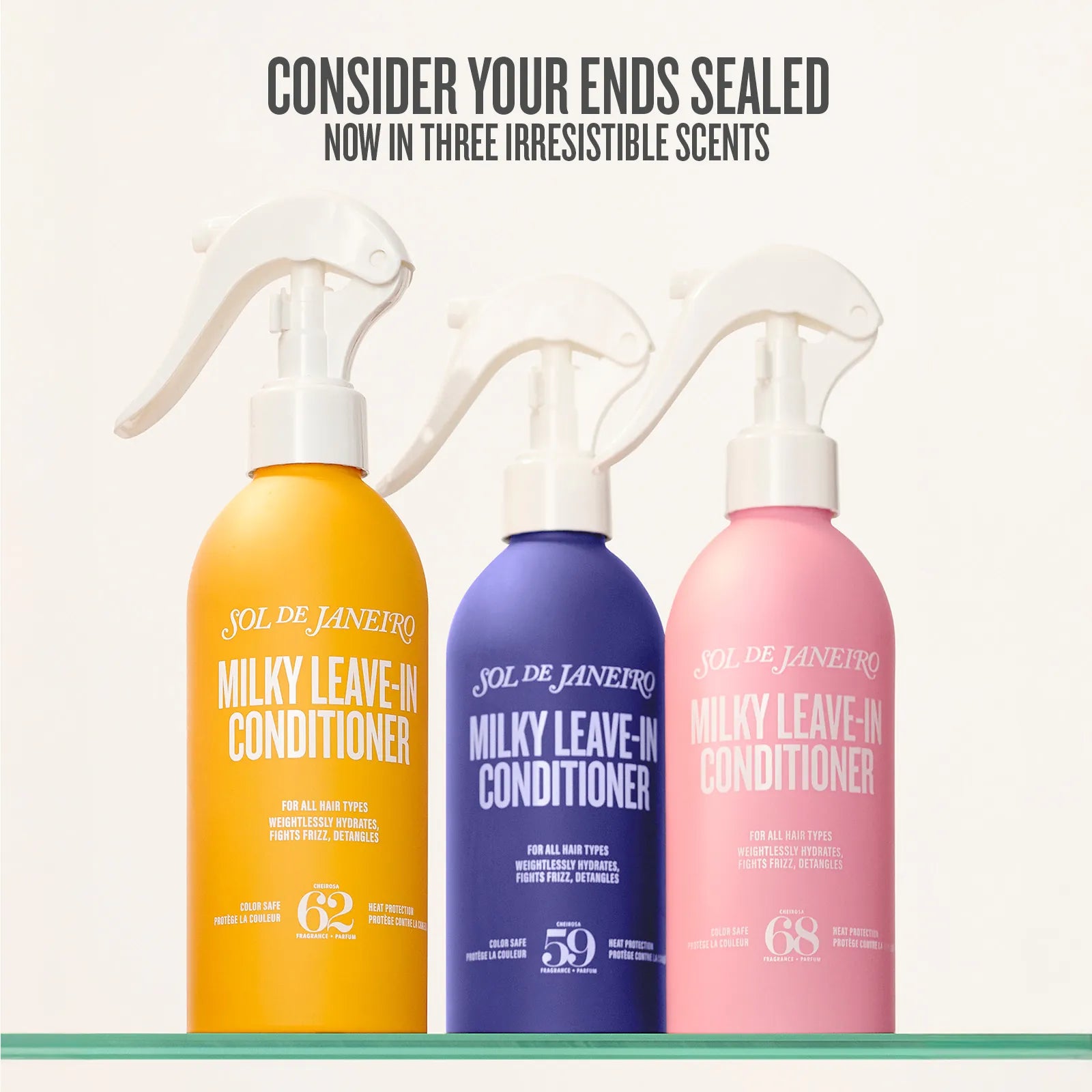 Three bottles of Sol de Janeiro Milky Leave-In Conditioner in yellow, purple, and pink on a white background.