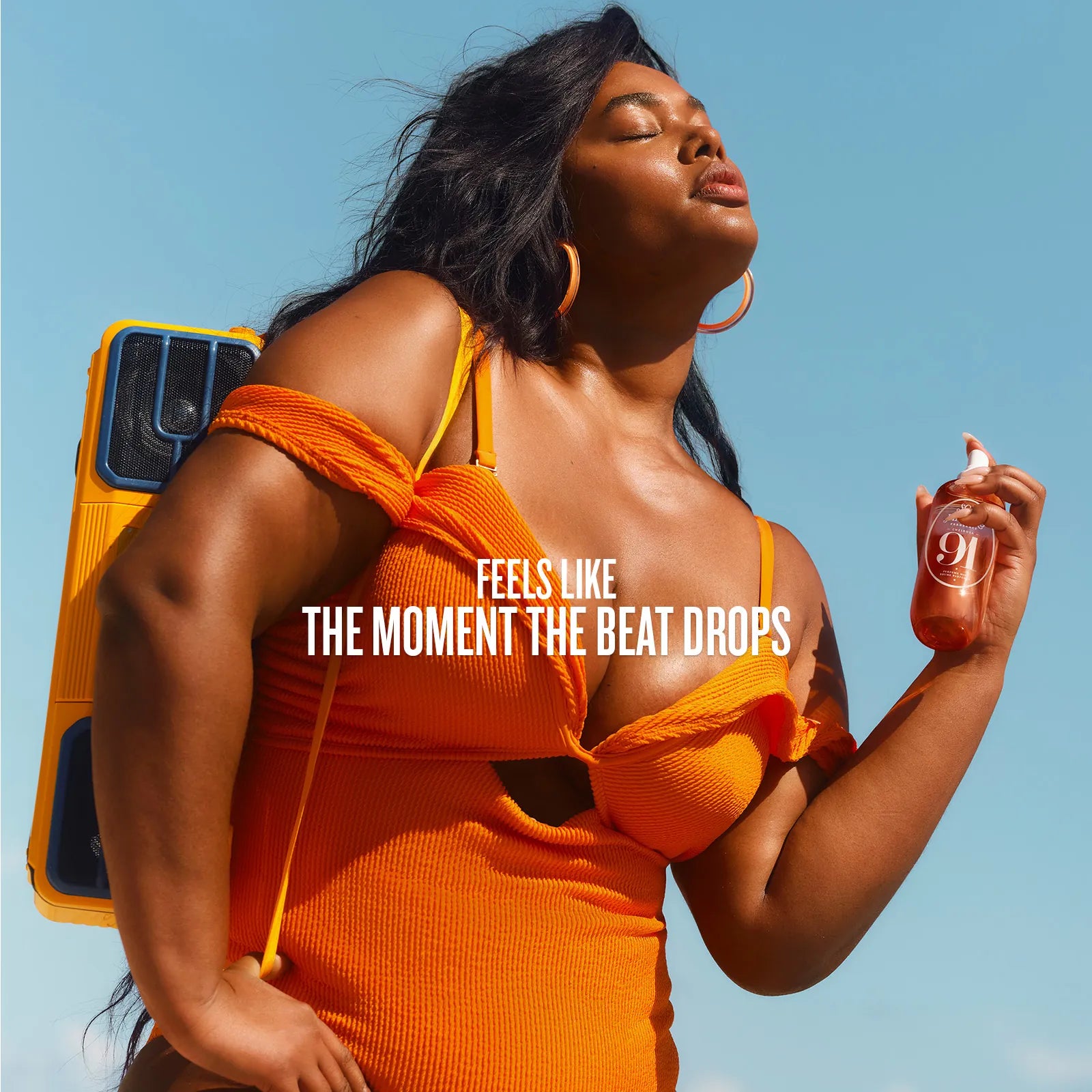 Woman in orange top holding a bottle with text 'Feels Like The Moment The Beat Drops' against a blue sky.